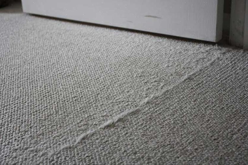 Centreer een lijn tapijtzoomband onder de twee afgesneden randen van de twee stukken tapijt